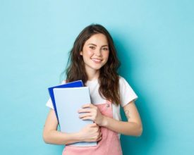 cute-smiling-girl-student-holding-notebooks-and-looking-cheerful-at-camera-studying-in-college-or-university-standing-over-blue-background-e1673427853556.jpg