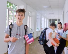 male-student-teenager-with-usa-flag-inside-college-group-of-students-background-united-states-of-america-education-and-youth-patriotism-people-concept.jpg